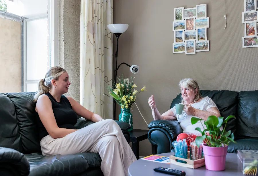 2 mensen met elkaar in gesprek in de woonkamer bij Beschermd wonen locatie