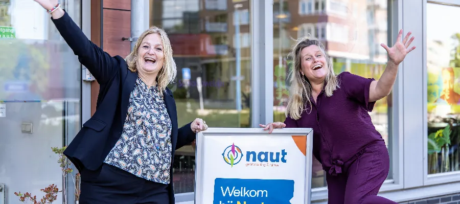 Collega's staan naast een welkomstbord van Naut